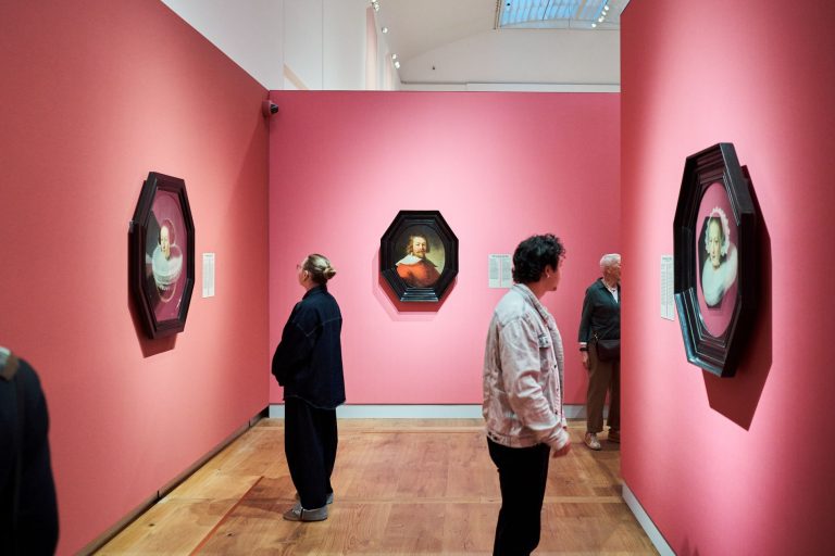 Twee bezoekers wandelen door de tentoonstelling Rembrandt tot Vermeer, meesterwerken van The Leiden Collection in H'ART Museum