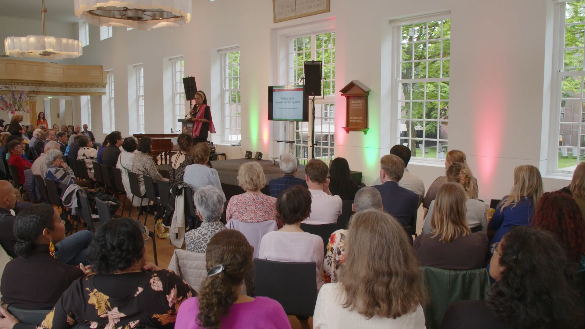 Moderator Aldith Hunkar spreekt een volle kerkzaal in H'ART Museum toe tijdens de Johan Ferrier Lezing 2023.