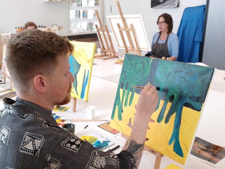 Jonge man maakt een schilderij tijdens een schilderworkshop in H'ART Museum Studio