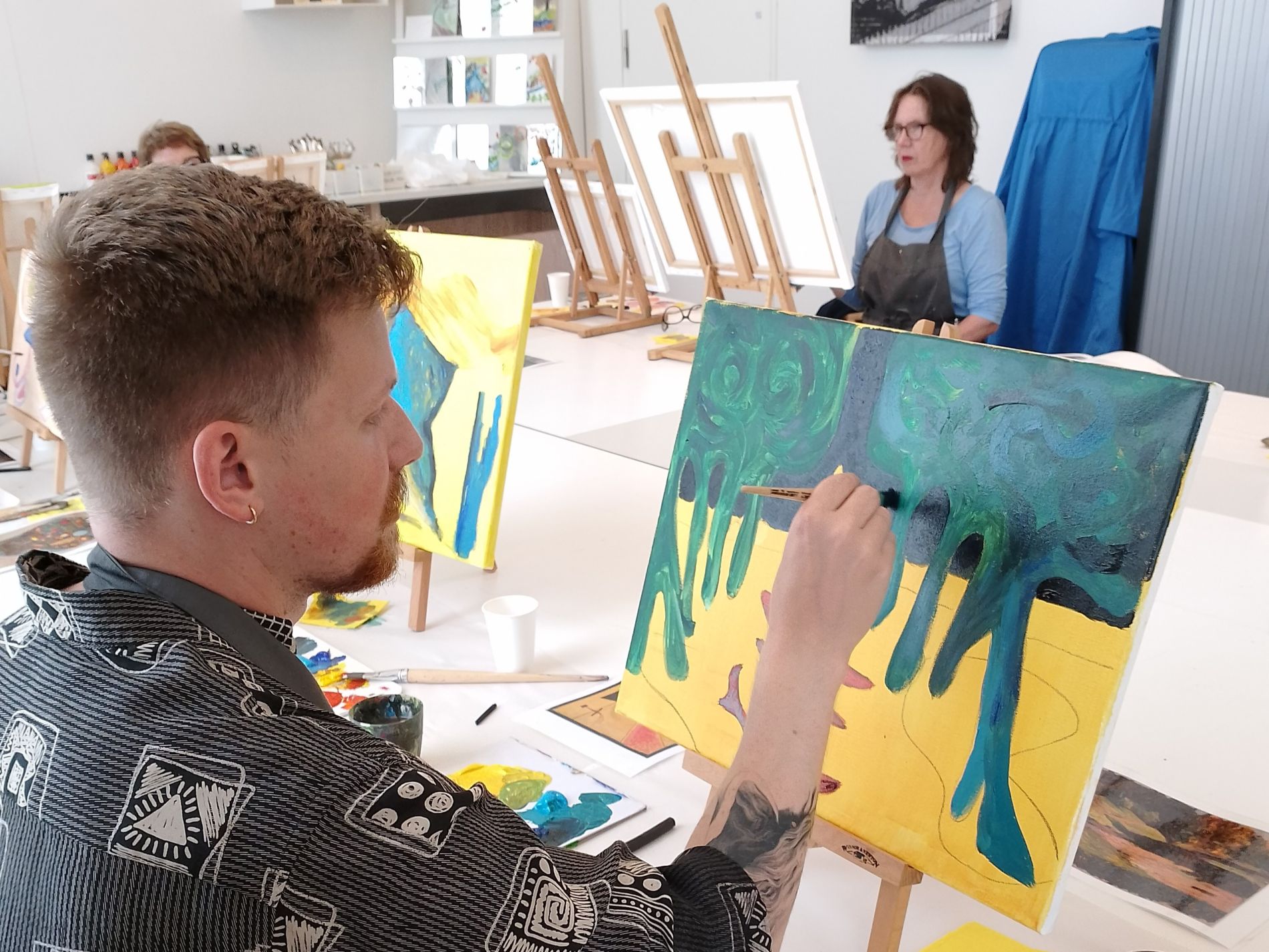 Jonge man maakt een schilderij tijdens een schilderworkshop in H'ART Museum Studio