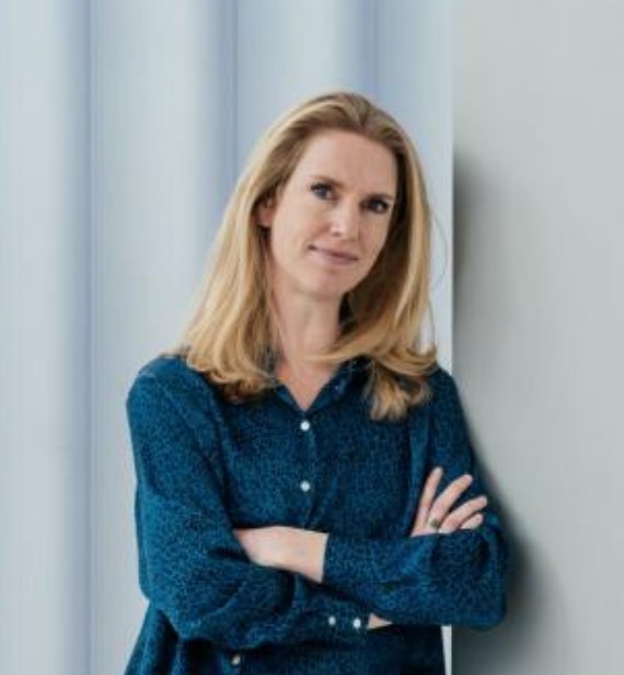 Portret foto van een glimlachende, blonde vrouw met haar armen gekruist.