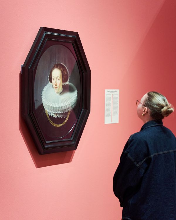 Jonge vrouw kijkt naar portret van een vrouw door Rembrandt van Rijn