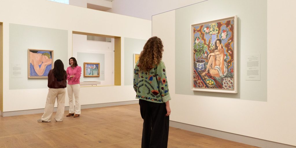 Bezoeker in de tentoonstelling Chez Matisse - Masterpieces from Centre Pompidou kijkt naar het werk Decoratieve figuur tegen een ornamentele achtergrond van Henri Matisse